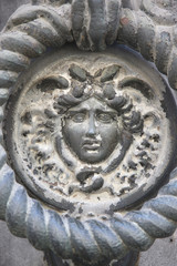 The decorative element of the handle of a massive metal gate in the form of a head of a mythical character