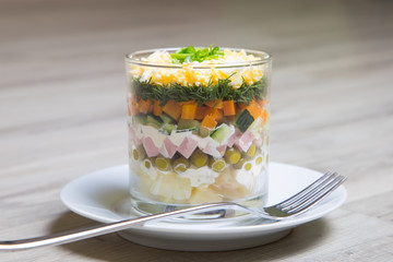 Traditional Russian salad Olivier with sausage in a glass. Selective focus, close - up.