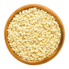 Blanched almonds, roughly chopped, in wooden bowl. Edible, dried seeds of Prunus dulcis. Ingredient in marzipan, nougat, cookies. Isolated macro food photo close up from above on white background.