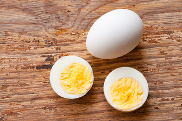 boiled egg cutout and raw egg with shell on wooden background