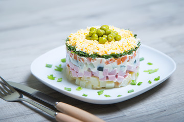 Traditional Russian salad olivier on a white plate. Selective focus, close-up.