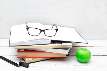 Stack of books for study and an apple on a white background