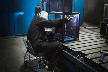 A man with a welding mask welding something together