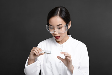 Horizontal shot of young Asian woman scientist analyzing cell culture samples, holding glass plate,...