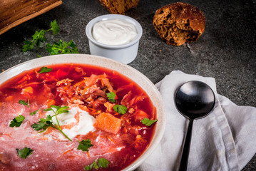 Traditional Ukrainian Russian vegetable soup borscht, with hard cream. parsley rye bread rolls, on black stone table, copy space