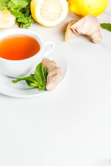 Cup of ginger tea with lemon,fresh mint and honey, on white marble table, copy space