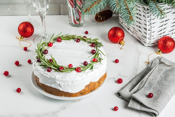 Christmas fruit cake or pudding, decorated with rosemary and cranberry, with christmas decoration, on white marble table, copy space