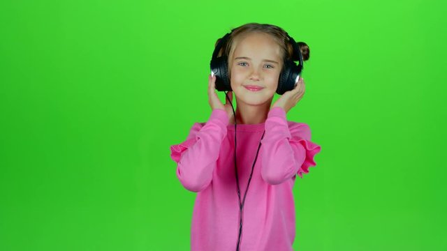 Baby listens to the music in the headphones. Green screen. Slow motion