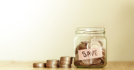  the money coins into the glass jar with label of SAVE word tag , money saving and financial concept