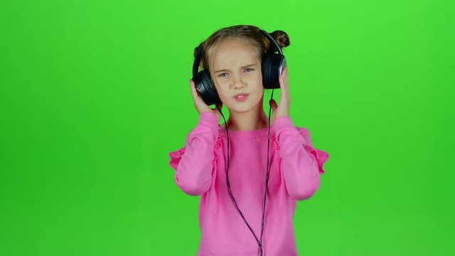 Child listens to the music in the headphones. Green screen. Slow motion