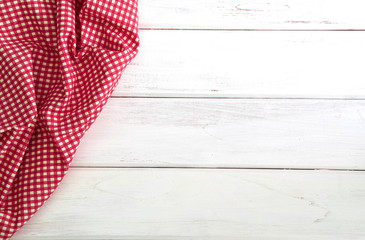 The Crumpled red checkered tablecloth or napkin on empty white wooden table with copy space for food cooking  menu background concept , top view or overhead shot