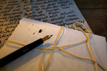ein Bündel antiker Briefe und Füller auf einem Holztisch