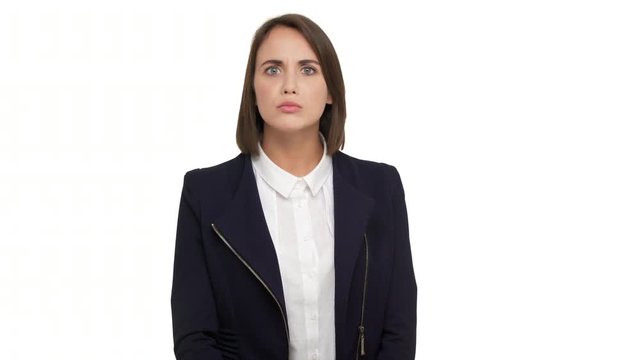 portrait of caucasian short-haired woman with beautiful blue eyes wearing business suit looking at camera with strict gaze holding index finger on lips asking to keep silence over white background in