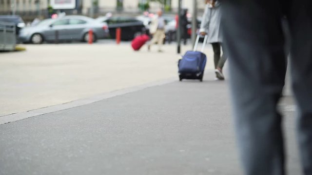 Many people walking near airport and rolling suitcases on caster wheels, travel