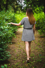 Девушка в платье идет по парку.
