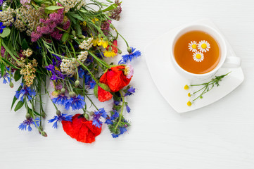 Chamomile, poppy, cornflower, yarrow and other beautiful summer field flowers with a cup of chamomile tea.