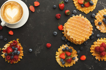 Round belgium waffles with berries, tasty breakfast on black background