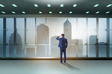 Businessman in front of office window thinking of new challenges