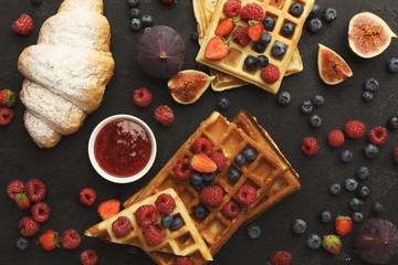 Belgium waffles with berries, tasty breakfast on black background