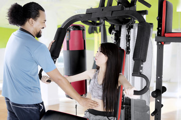 Young man helping woman doing exercise