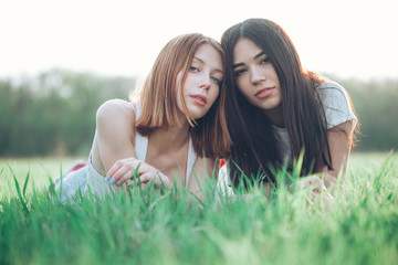 Two beautiful young woman lie on the grass
