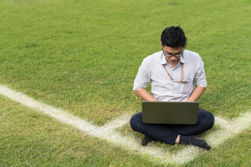 business man is sitting work with computer laptop on soccer field. working concept. copy space for conceptual message.