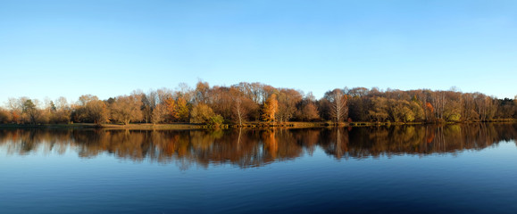 Beautiful countryside landscape with park after river under clear blue sky in autumn day panoramic photo