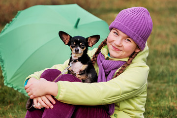girl in hat outdoors with a small dog.smiling teenage girl relaxing with dog