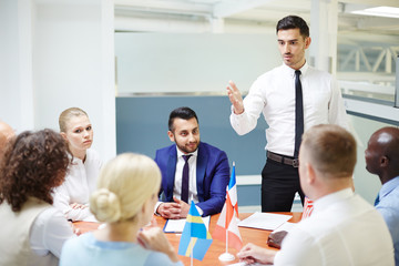 Confident politician voicing his point of view to colleagues from other countries at briefing