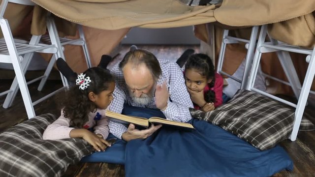 Old man reading the Bible with grandchildren