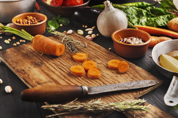 Sliced carrots with knife on wooden cutting board, background