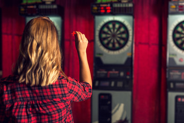 Fototapeta na wymiar Rear view of a woman playing darts