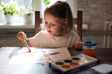 A little girl  drawing with watercolors