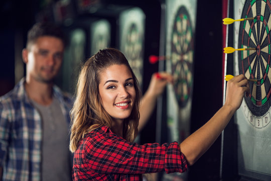 Happy woman playing darts