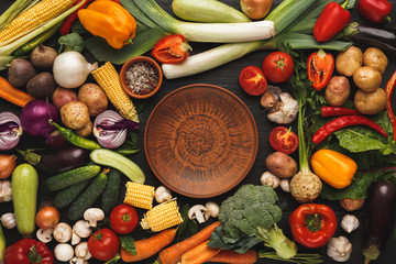 Fresh organic vegetables and brown plate background
