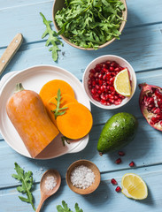 Ingredients for cooking grilled butternut squash, arugula and pomegranate salad on a blue wooden table, top view. Clean, organic, seasonal, vegetarian food concept