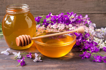 Obraz na płótnie Canvas Jar of honey with wildflowers on a dark wooden background
