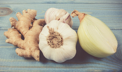 Garlic bulbs, ginger and onion on blue wooden table. Natural medicine.
