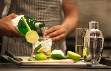 A professional bartender is making cocktails for customers. Meticulously