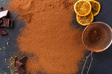 Cocoa powder in a sieve over black slate background