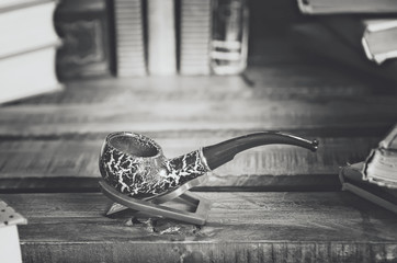 Books and a smoking pipe on a wooden table. Beautiful stylish composition. Вlack and white photography.