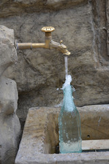 Auffüllen einer Wasserflasche am Brunnen