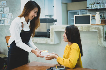 Asian barista serving a cup of coffee to customer. Cafe restaurant service, food and drink industry concept.