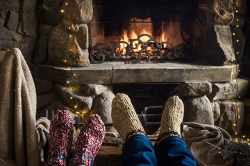 Closeup of two persons legs in knitted handmade socks near fireplace