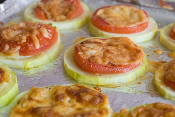 Slices of tomato and zucchini under cheese crust