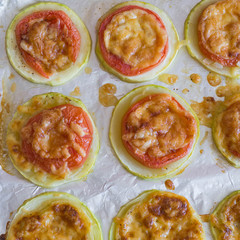 Slices of tomato and zucchini under cheese crust