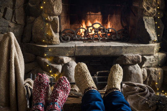 Closeup of two persons legs in knitted handmade socks near fireplace