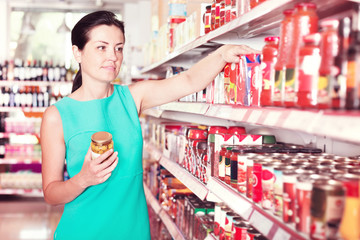 Woman readig label on jar of tomato sauce