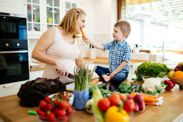 Pregnant woman preparing meal with son