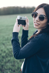 Young woman in round glasses with a camera outdoors